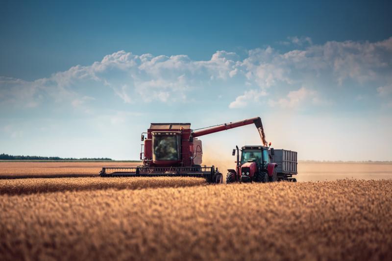 Combine harvester and tractor in field 