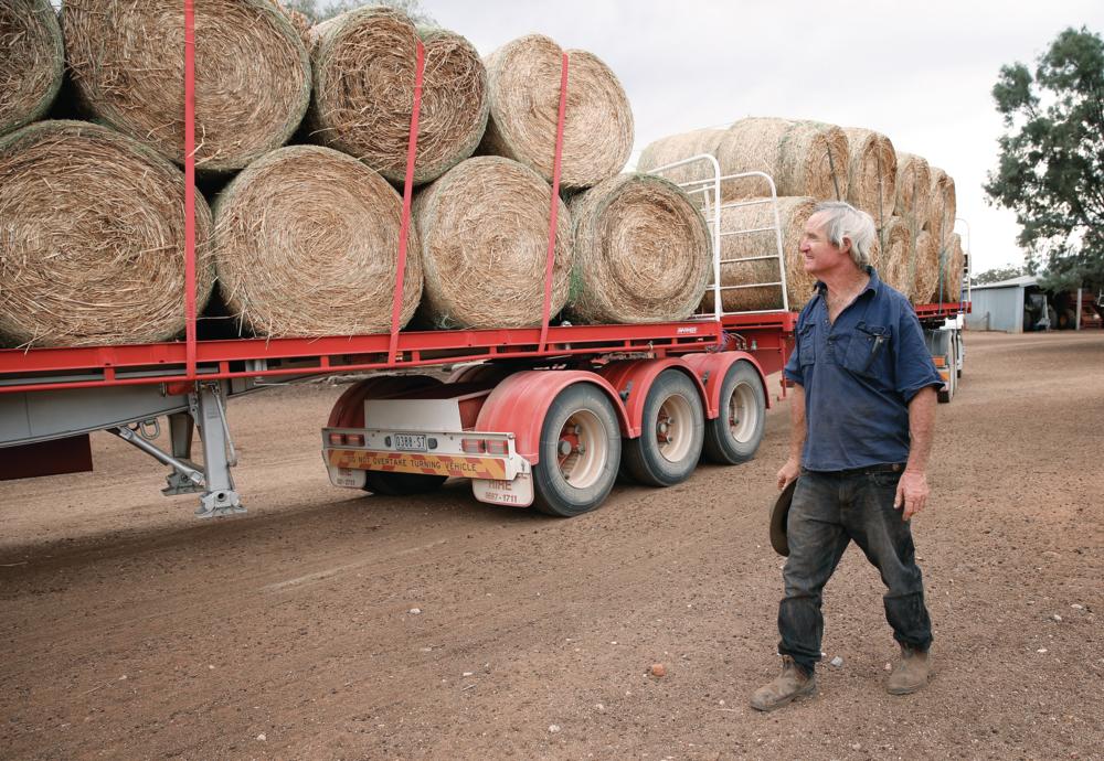 Farmer Les Jones looks on as hay from Victoria is delivered to his farm in Goolhi NSW